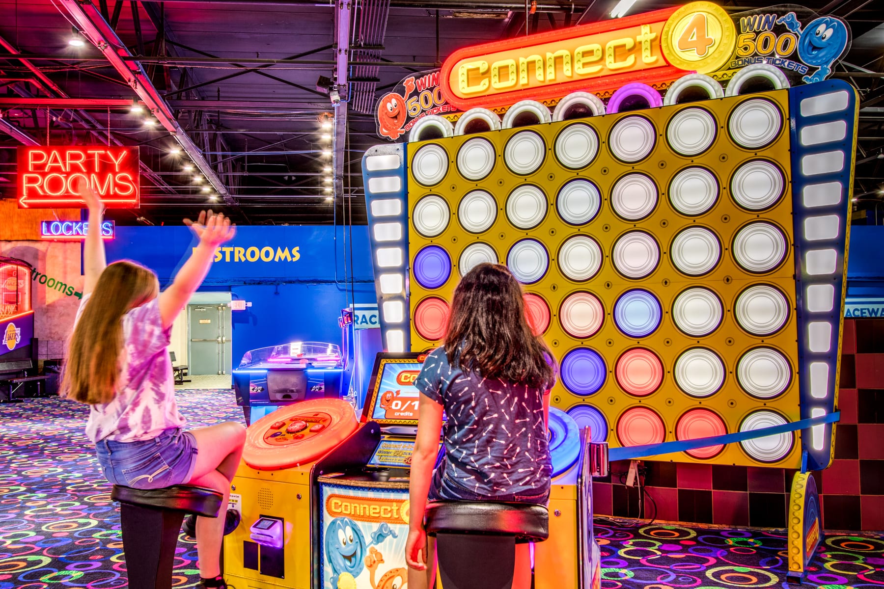 Two girls playing a game at an amusement park.