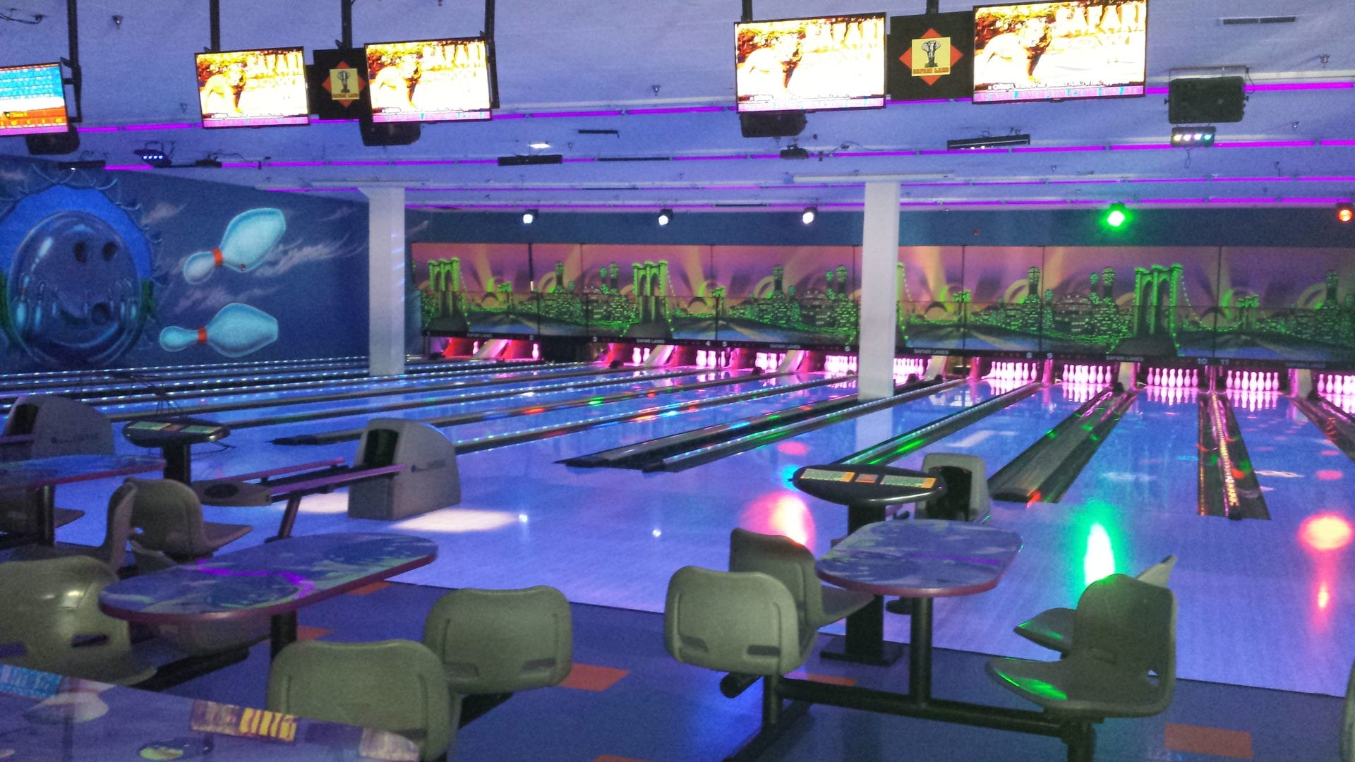 A bowling alley with many lanes and tables.